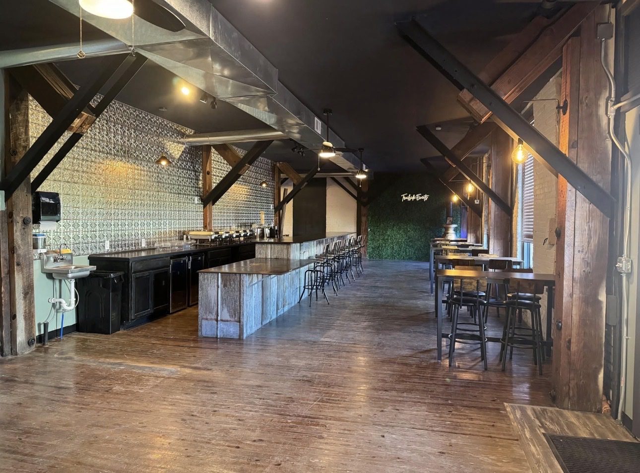 The TrailSide room: timber posts, a full-length bar, and tables along the brick wall.